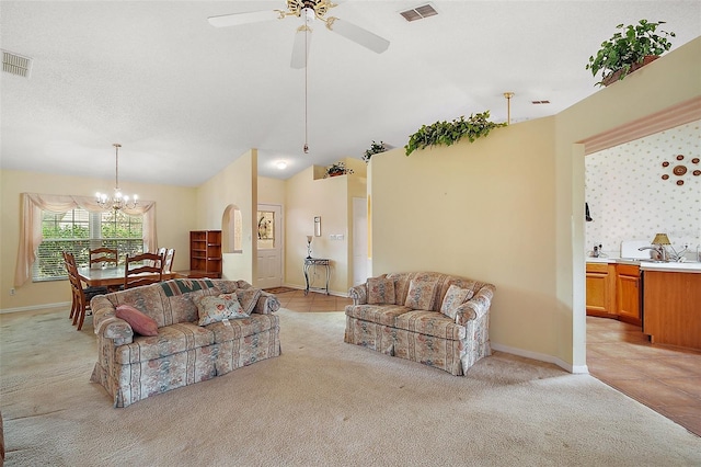 living room with visible vents, arched walkways, ceiling fan with notable chandelier, and light colored carpet