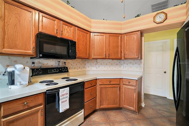 kitchen featuring black appliances, light tile patterned flooring, light countertops, and brown cabinets