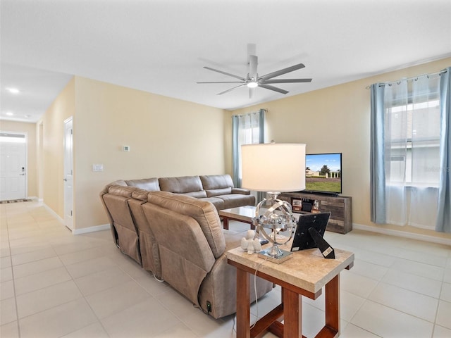 living area featuring baseboards, light tile patterned floors, and a ceiling fan