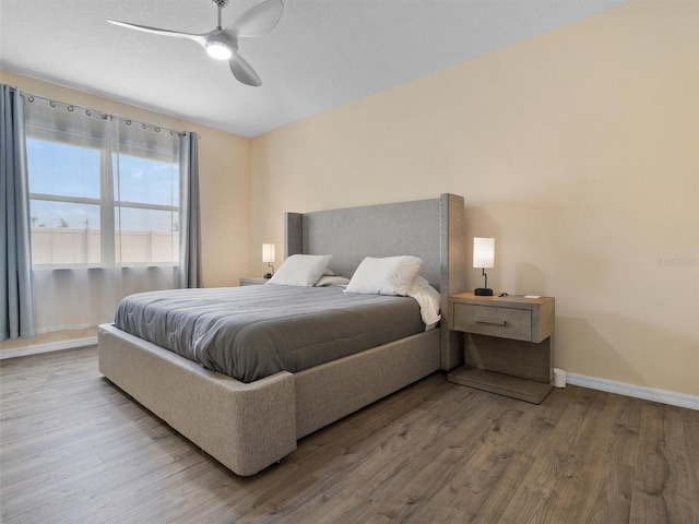 bedroom with a ceiling fan, wood finished floors, and baseboards