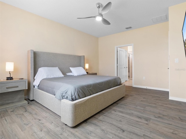 bedroom with baseboards, visible vents, and wood finished floors