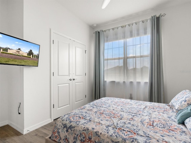 bedroom with a closet, wood finished floors, and baseboards