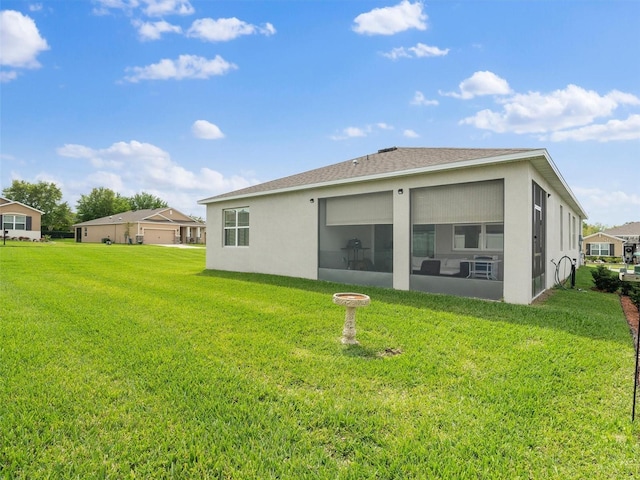 back of house featuring stucco siding, a lawn, and a sunroom