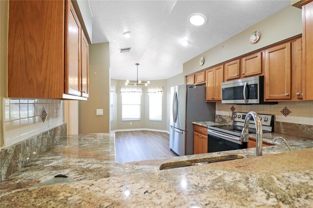 4848 Saint Andrews Arc, Leesburg, FL 34748 - kitchen with brown cabinets, decorative backsplash, stainless steel appliances, a notable chandelier, and visible vents