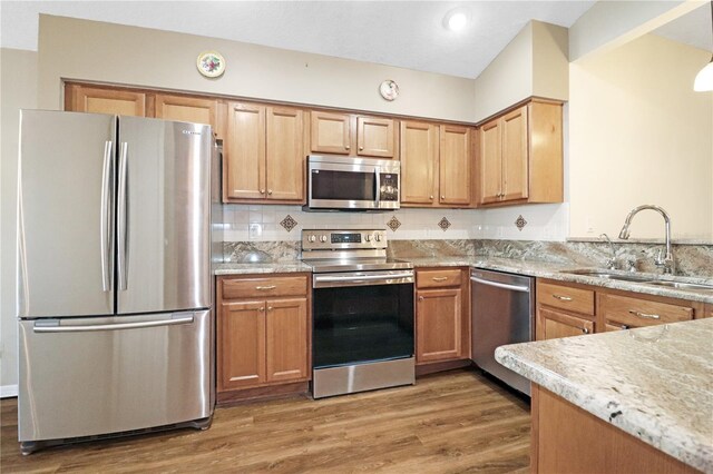 4848 Saint Andrews Arc, Leesburg, FL 34748 - kitchen featuring appliances with stainless steel finishes, light stone counters, light wood-style flooring, and a sink