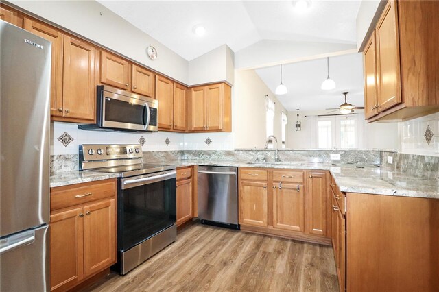 4848 Saint Andrews Arc, Leesburg, FL 34748 - kitchen with stainless steel appliances, light wood-style floors, vaulted ceiling, a sink, and a ceiling fan