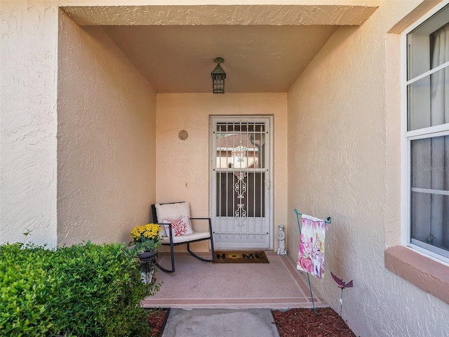 doorway to property with stucco siding and a porch