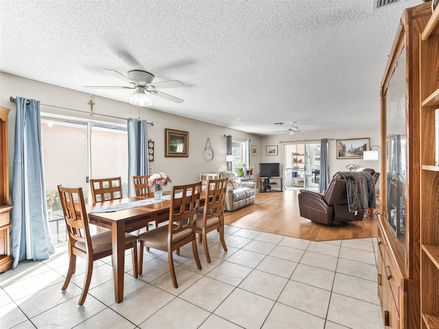 dining area with a textured ceiling, ceiling fan, and light tile patterned floors
