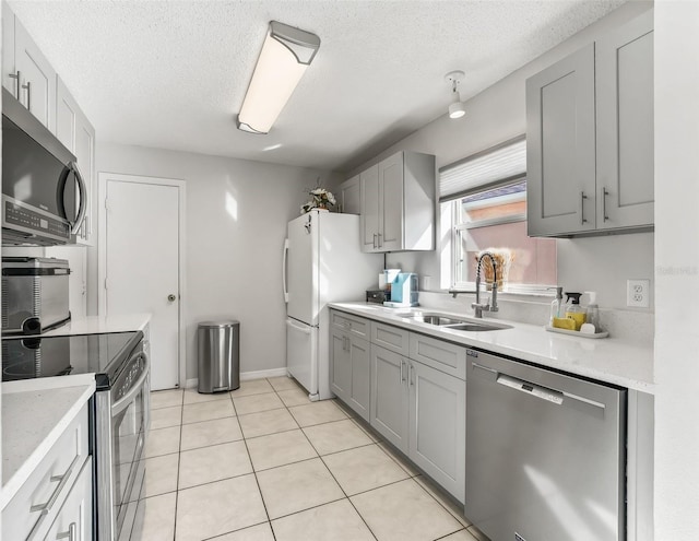 kitchen featuring a sink, gray cabinetry, stainless steel appliances, and a textured ceiling
