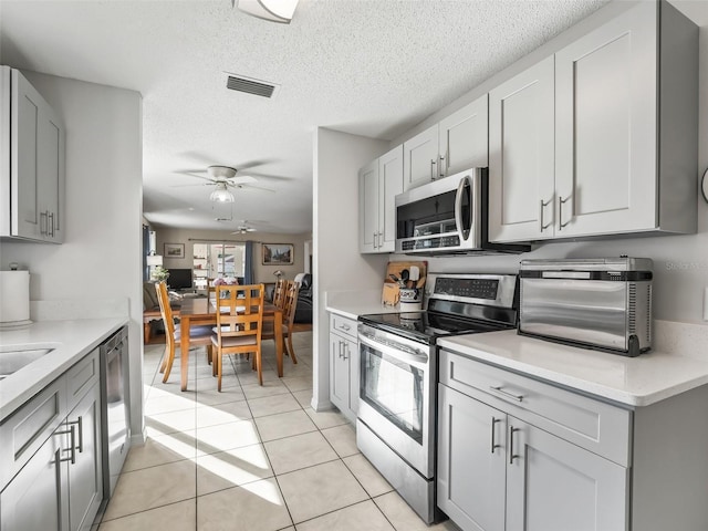 kitchen featuring visible vents, light countertops, a ceiling fan, light tile patterned floors, and stainless steel appliances