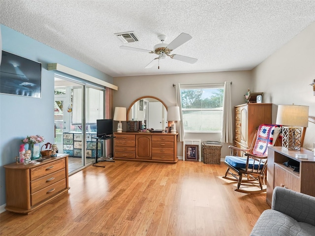 interior space with a textured ceiling, visible vents, ceiling fan, and light wood-style floors