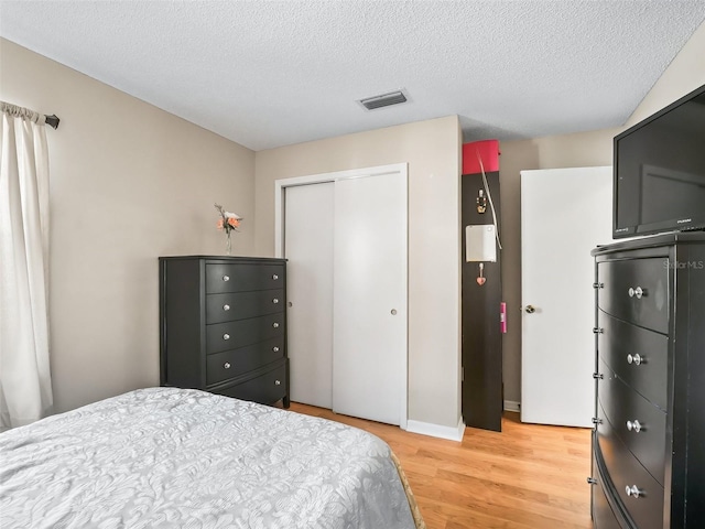 bedroom with visible vents, a textured ceiling, a closet, and light wood-type flooring