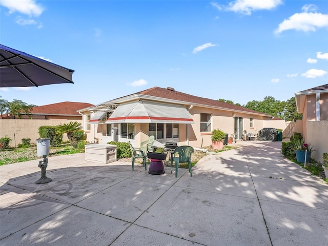 rear view of house featuring a patio, fence, and stucco siding