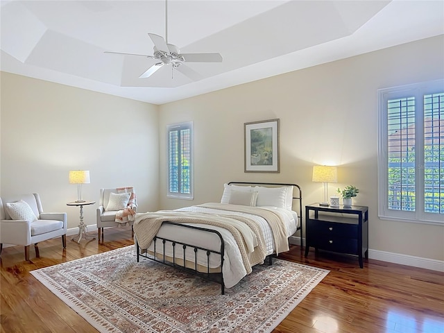 1842 Lake Ridge Dr, The Villages, FL 32162 - bedroom featuring baseboards, wood finished floors, a tray ceiling, and multiple windows