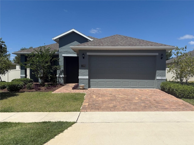 prairie-style house with an attached garage, decorative driveway, stucco siding, and a front yard