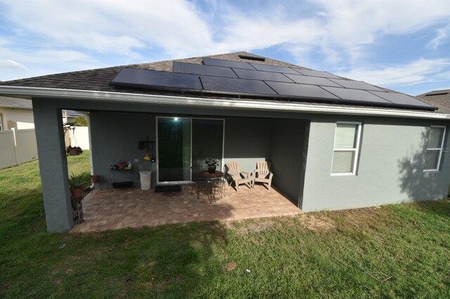 709 Calabria Way, Howey In The Hills, FL 34737 - rear view of house featuring roof with shingles, a patio, roof mounted solar panels, and stucco siding