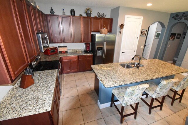 709 Calabria Way, Howey In The Hills, FL 34737 - kitchen featuring stainless steel appliances, a sink, arched walkways, a kitchen bar, and light tile patterned floors