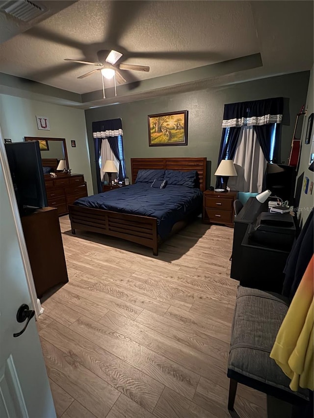 709 Calabria Way, Howey In The Hills, FL 34737 - bedroom featuring wood finished floors, a textured ceiling, a tray ceiling, and ceiling fan