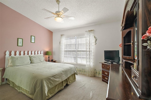 bedroom featuring a ceiling fan, a textured ceiling, and light carpet