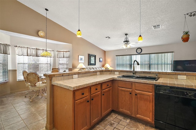 kitchen featuring a ceiling fan, visible vents, a sink, tile counters, and black dishwasher
