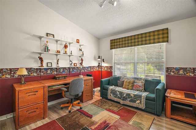 office featuring a textured ceiling, vaulted ceiling, wainscoting, and light wood-style flooring