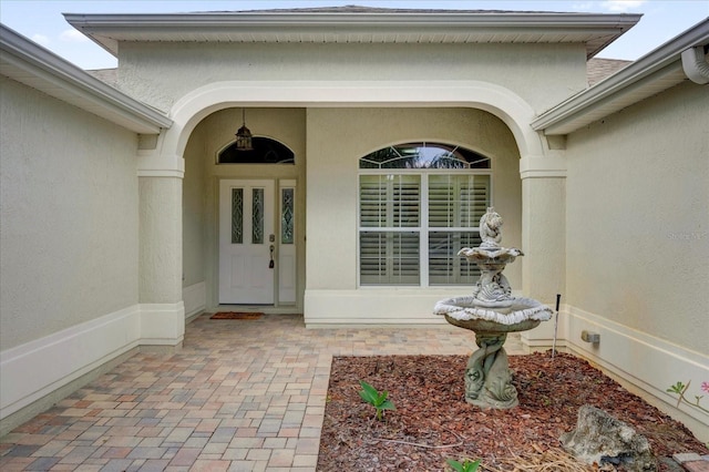 property entrance featuring stucco siding and covered porch