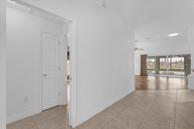 hall featuring baseboards, attic access, and light tile patterned flooring