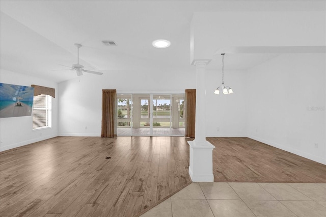 unfurnished living room with wood finished floors, visible vents, a wealth of natural light, and decorative columns