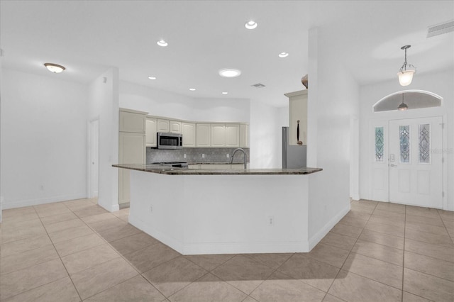 kitchen featuring stainless steel microwave, decorative backsplash, light tile patterned flooring, visible vents, and a peninsula