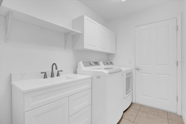 laundry room with light tile patterned floors, washing machine and dryer, cabinet space, and a sink