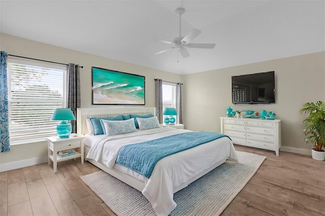 bedroom with baseboards, ceiling fan, and light wood-style flooring