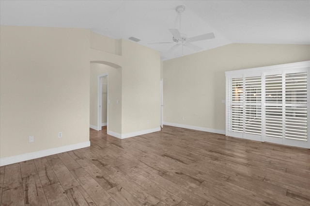 empty room with visible vents, arched walkways, vaulted ceiling, wood finished floors, and a ceiling fan