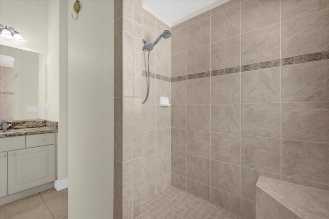 full bathroom featuring a tile shower, vanity, and tile patterned flooring