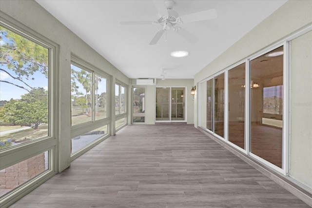 unfurnished sunroom featuring wood finished floors and a wall unit AC