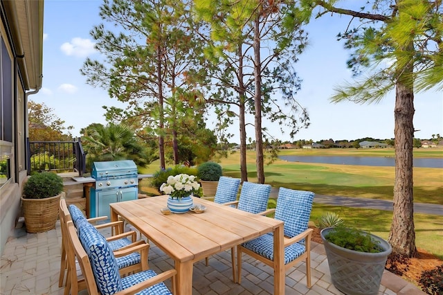 view of patio / terrace with view of golf course, exterior kitchen, area for grilling, a water view, and outdoor dining space