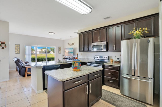 2641 Meadow View Ct, Kissimmee, FL 34746 - kitchen featuring appliances with stainless steel finishes, light tile patterned floors, a peninsula, and dark brown cabinets