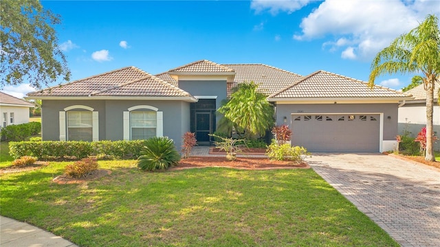 2641 Meadow View Ct, Kissimmee, FL 34746 - mediterranean / spanish house with stucco siding, a garage, a tiled roof, a front yard, and decorative driveway