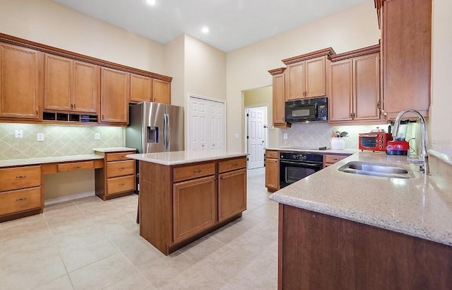 kitchen featuring a kitchen island, light stone countertops, a sink, backsplash, and black appliances