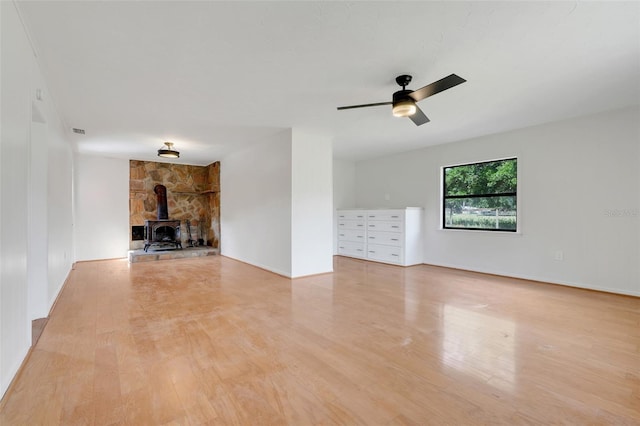 274 W Kings Hwy, Center Hill, FL 33514 - unfurnished living room with visible vents, a wood stove, light wood-style flooring, and ceiling fan