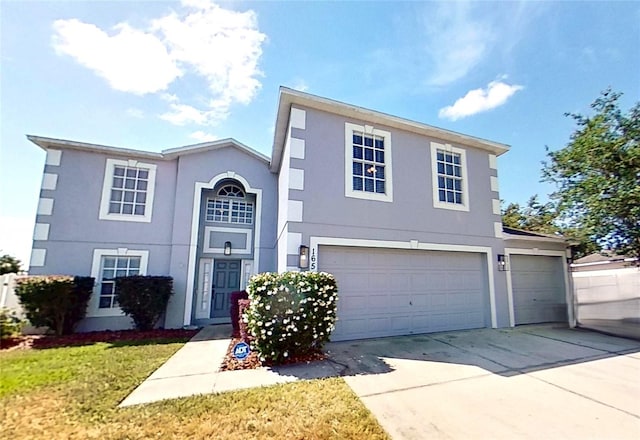 traditional home with concrete driveway, a front yard, an attached garage, and stucco siding