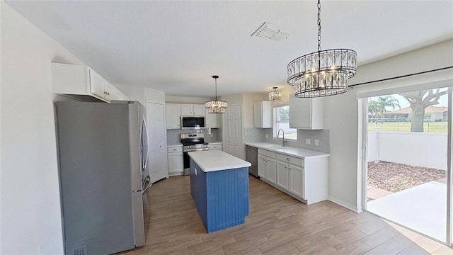 kitchen with a sink, an inviting chandelier, tasteful backsplash, visible vents, and appliances with stainless steel finishes