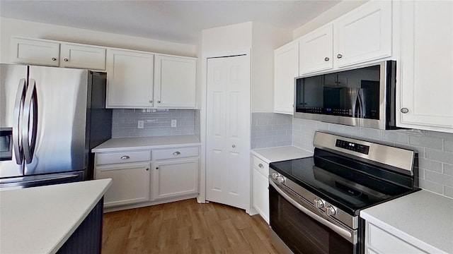 kitchen featuring decorative backsplash, white cabinets, appliances with stainless steel finishes, light wood-style floors, and light countertops