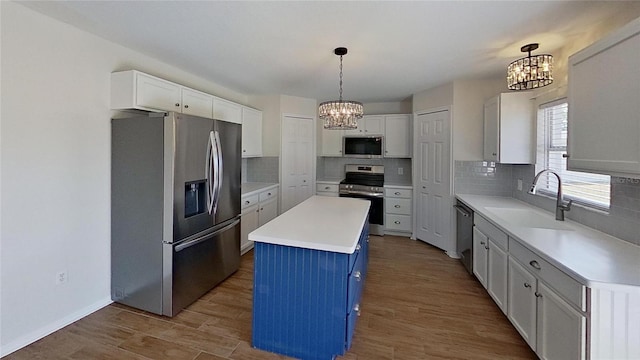 kitchen with a sink, a chandelier, a kitchen island, and stainless steel appliances