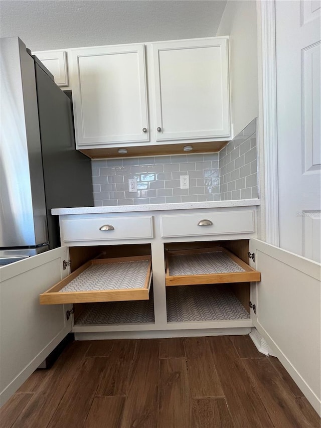 room details with dark wood-style flooring, white cabinets, decorative backsplash, and light countertops