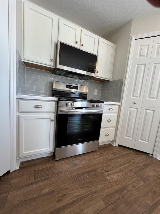kitchen with dark wood finished floors, white cabinets, stainless steel appliances, and light countertops
