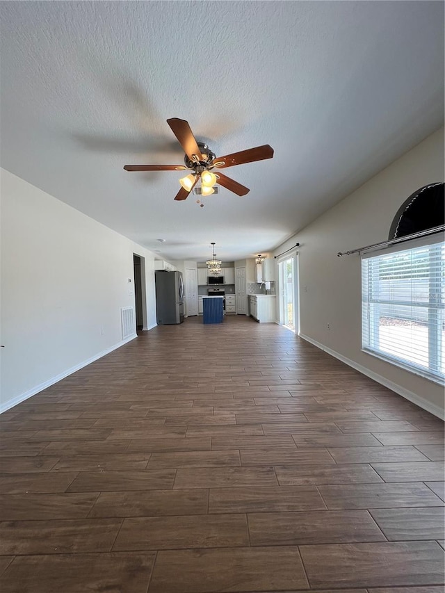 unfurnished living room featuring wood tiled floor, ceiling fan, visible vents, and baseboards