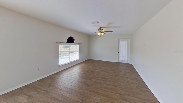 empty room with wood finished floors, visible vents, ceiling fan, and baseboards