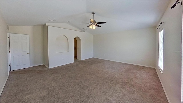 carpeted spare room with a ceiling fan, visible vents, vaulted ceiling, baseboards, and arched walkways