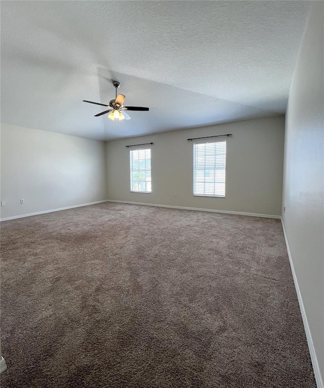 carpeted spare room featuring baseboards, ceiling fan, and a textured ceiling