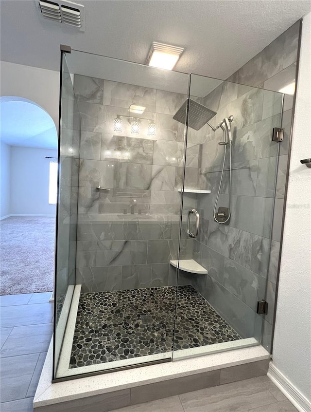 bathroom with baseboards, visible vents, a shower stall, and a textured ceiling